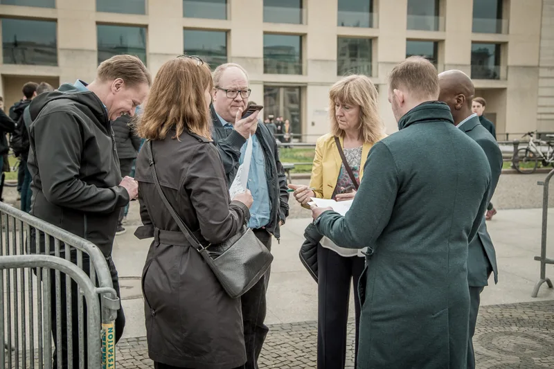 Colleagues reading their treasure hunt clues together on Pariser Platz in Berlin