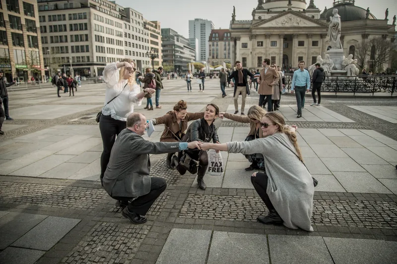 A team completing a photo challenge on Gendarmenmarkt in front of one of its twin domed cathedrals