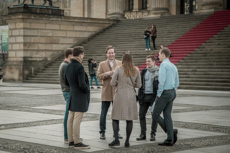 Colleagues chatting on Gendarmenmarkt in front of the Konzerthaus steps during a corporate event in Berlin
