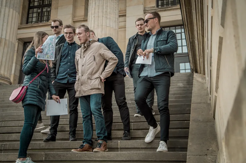 Treasure hunt team with a map and clue sheets on the steps of the Konzerthaus in Berlin