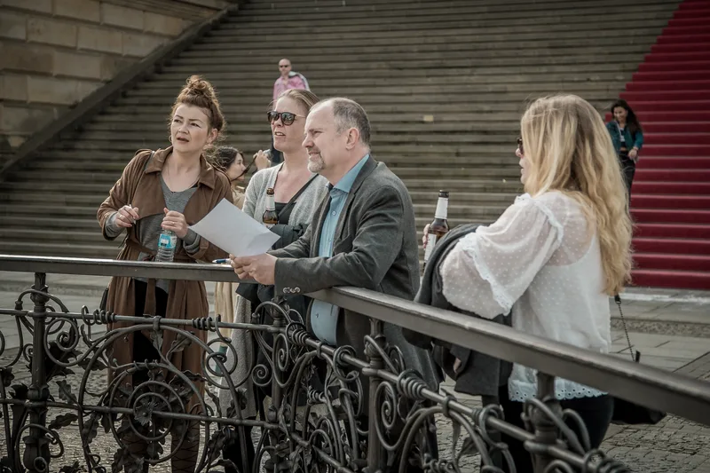 Treasure hunt team reading a clue at the railing by the Konzerthaus steps on Gendarmenmarkt