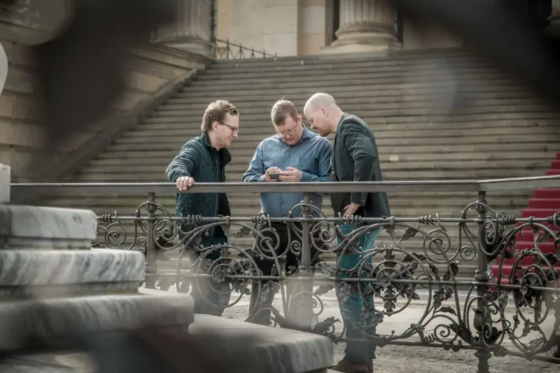 Three colleagues studying the treasure hunt booklet