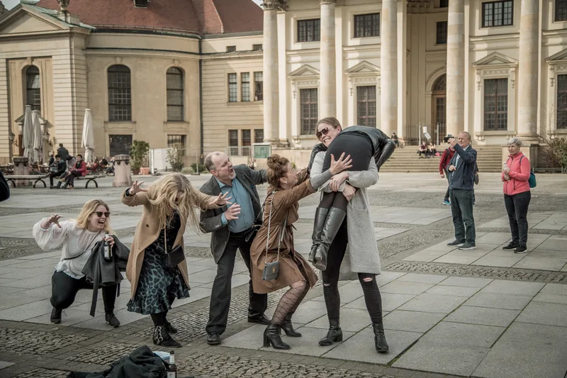 Colleagues acting out a playful photo challenge on Gendarmenmarkt during a treasure hunt in Berlin