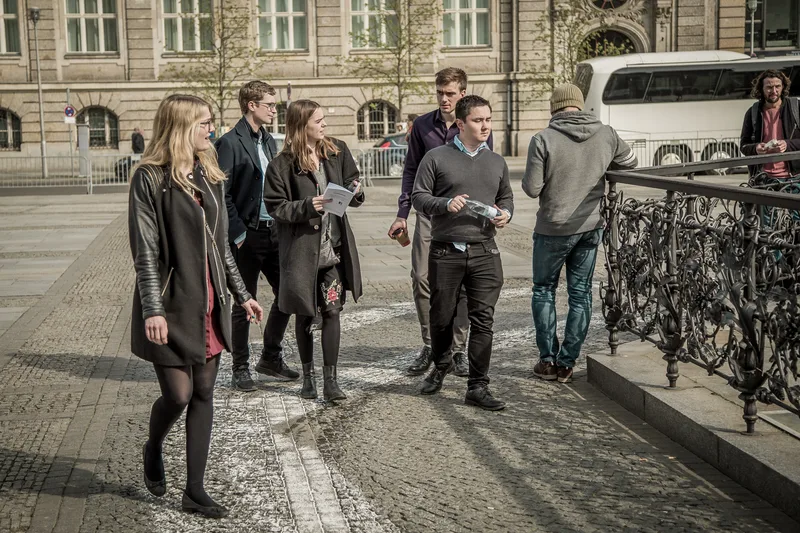 Treasure hunt team walking across Gendarmenmarkt with their clue sheets on a sunny day in Berlin