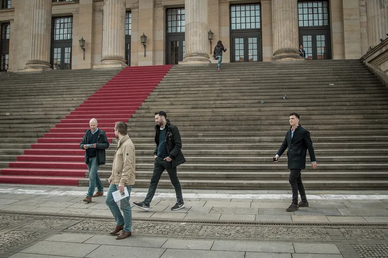 Treasure hunt players walking past the red-carpeted steps of the Konzerthaus on Gendarmenmarkt