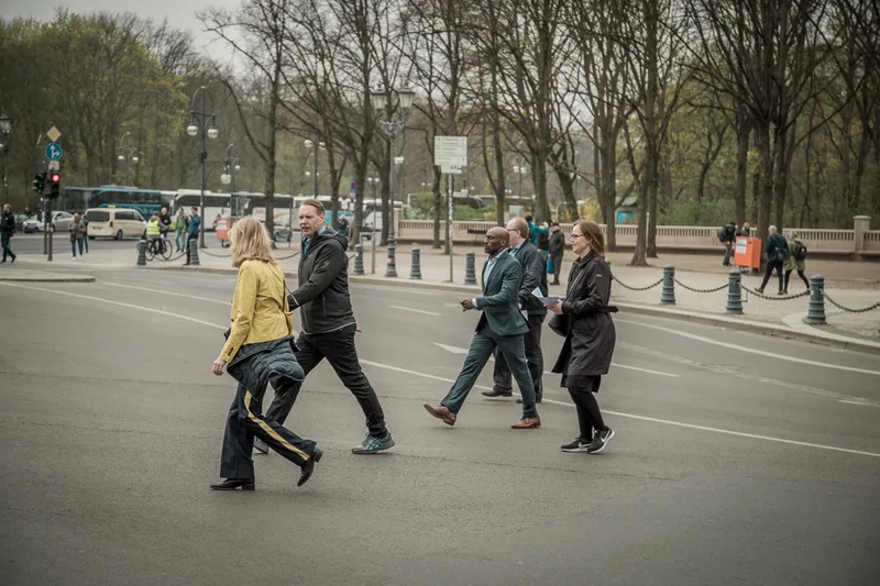 Treasure hunt teams crossing the street near the Brandenburg Gate with their clue sheets