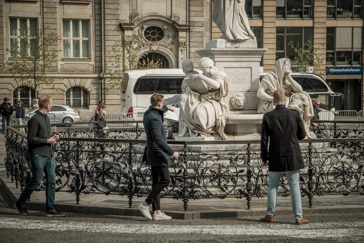 Treasure hunt players with a map at the Schiller Monument on Gendarmenmarkt, Berlin